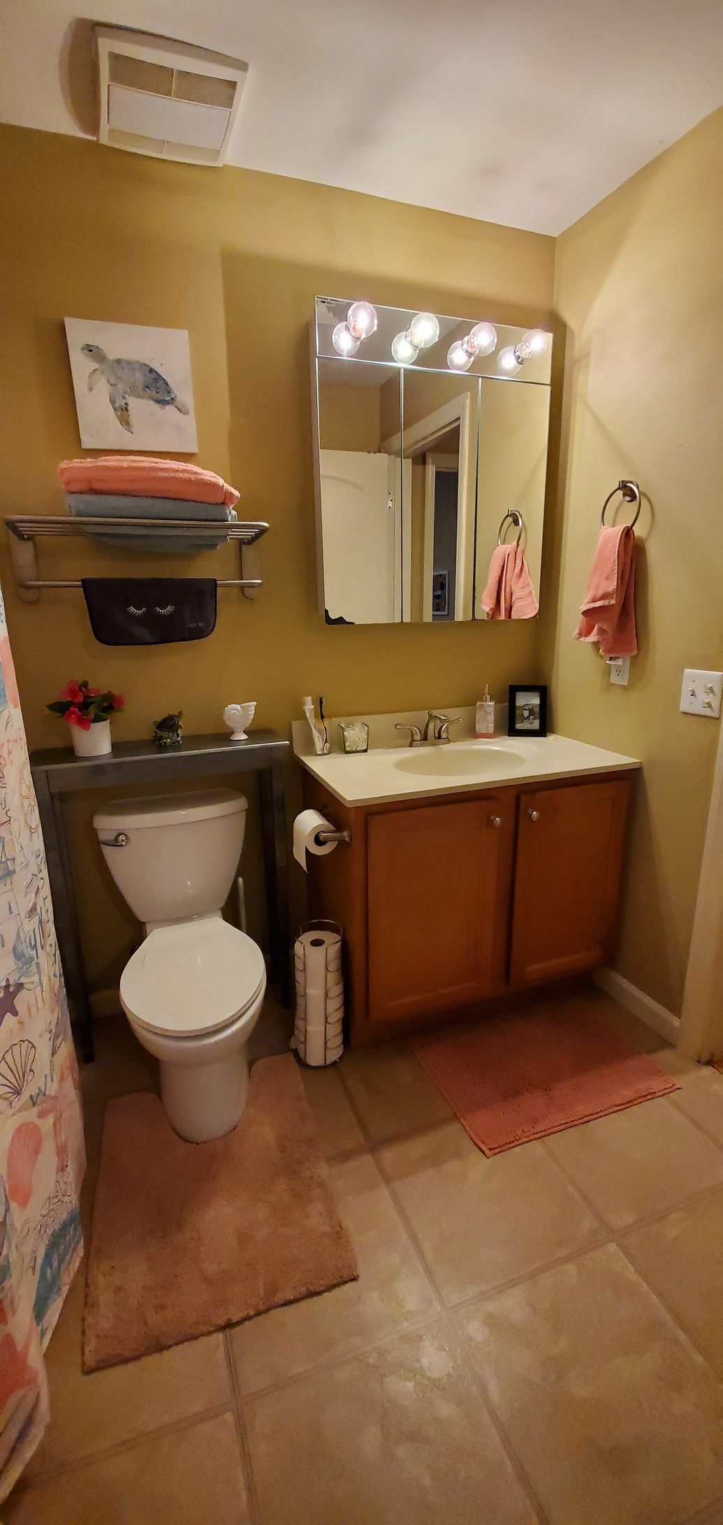 A bathroom with a toilet , sink and mirror.