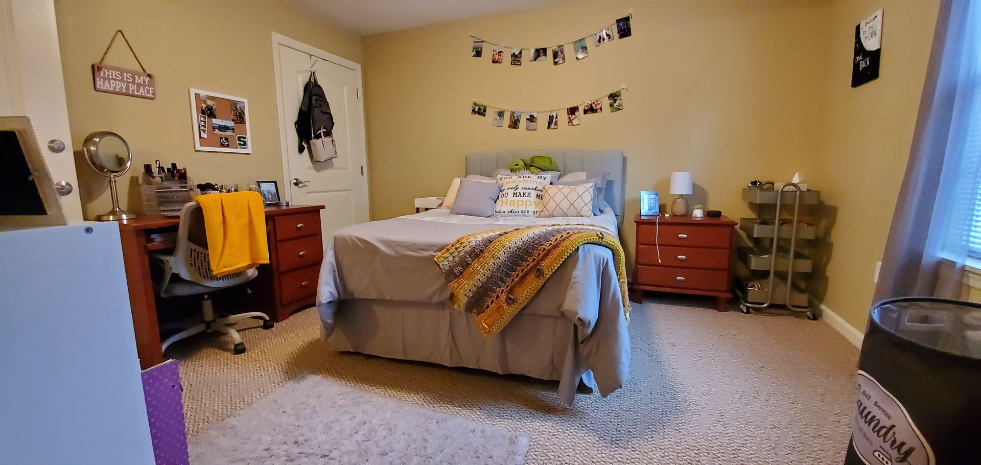 A bedroom with a bed , desk , nightstands , and a fan.