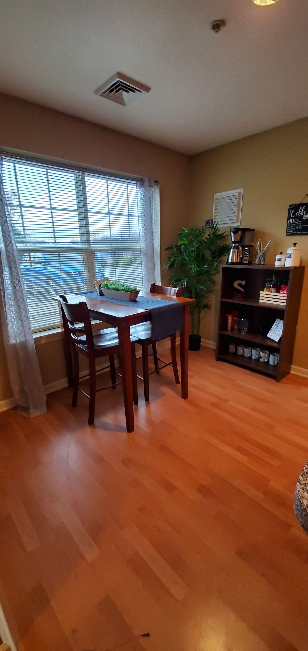A dining room with a table and chairs in front of a window.