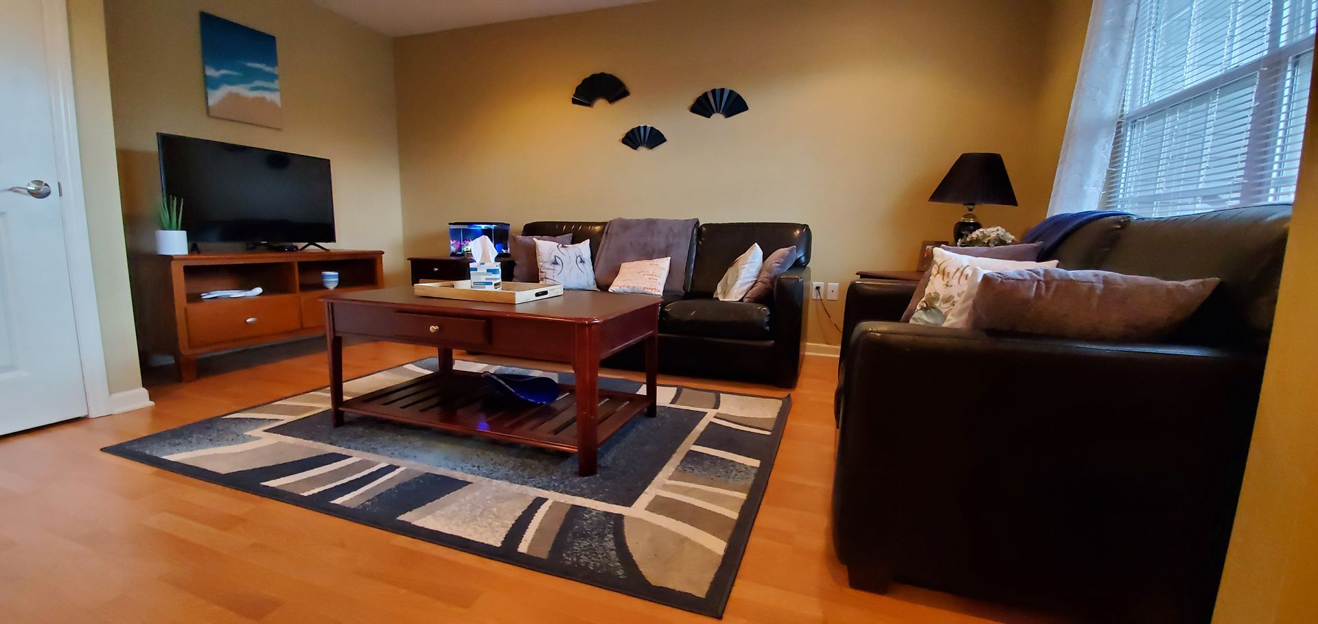 A living room with a couch , chair , coffee table and television.
