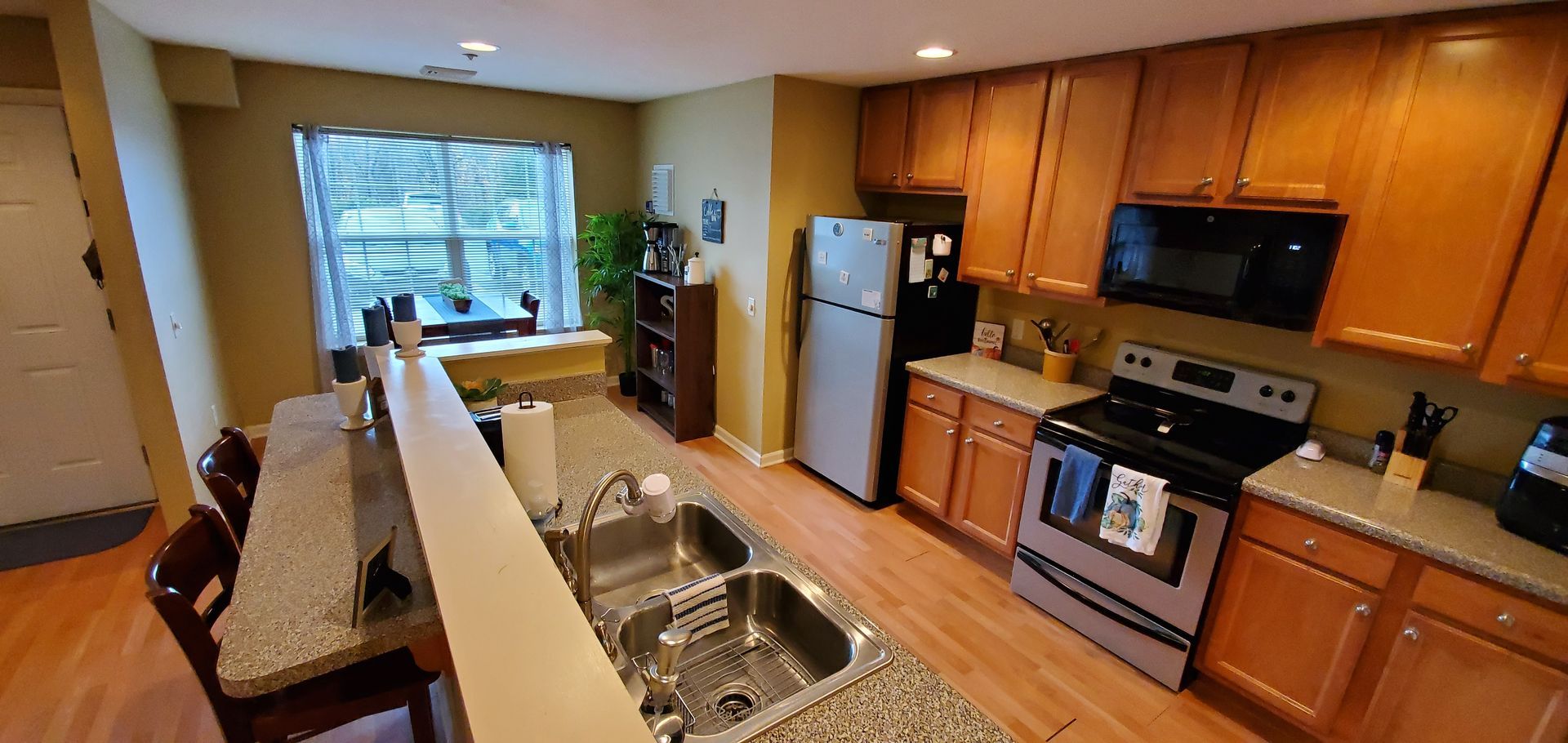 A kitchen with a sink , stove , refrigerator and microwave.