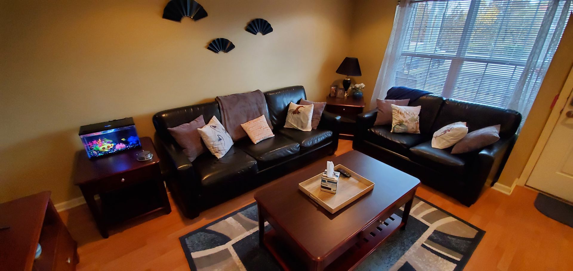 A living room with two couches , a coffee table , and a fish tank.