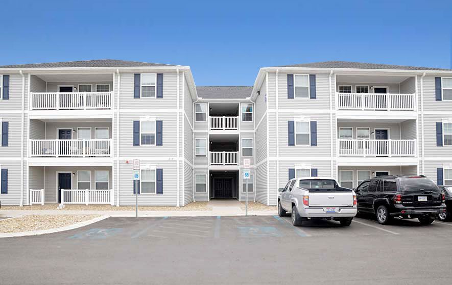 A large apartment building with cars parked in front of it.
