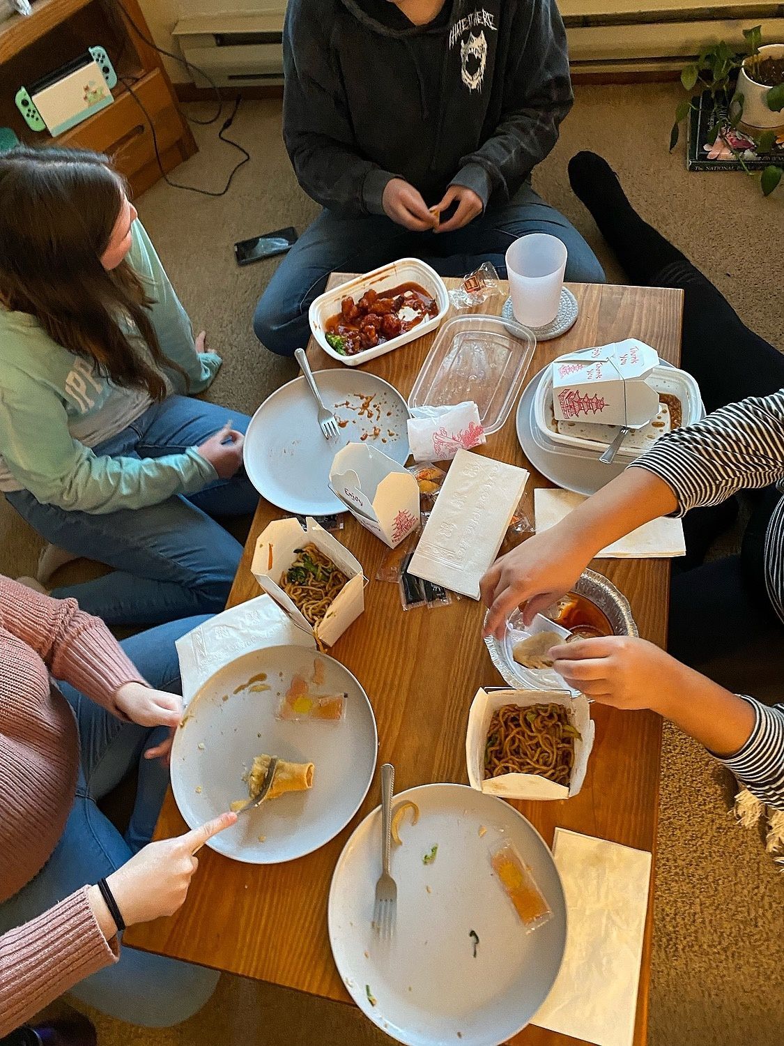 A group of people are sitting around a table eating food.