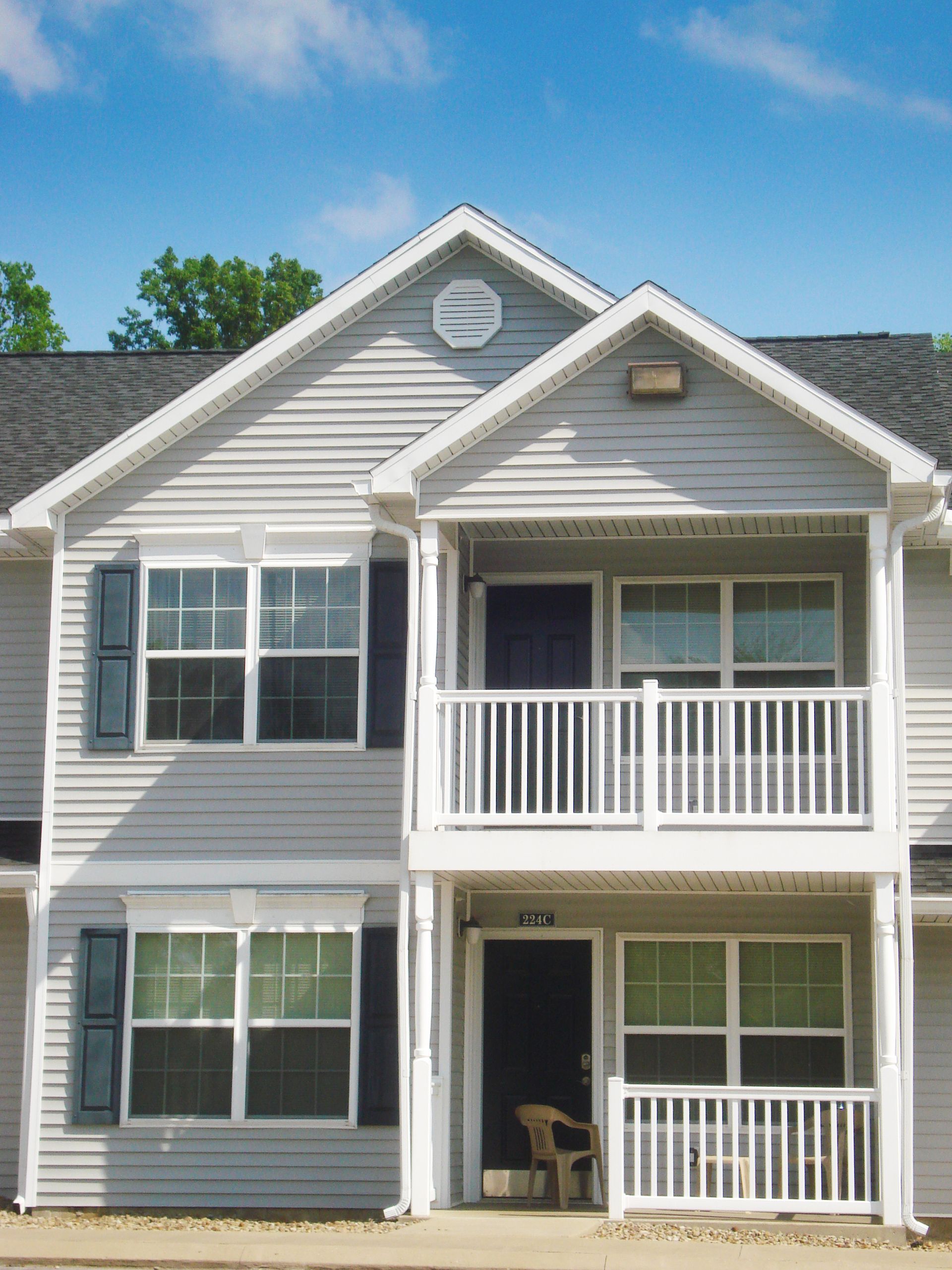 A white house with a balcony and a blue sky in the background