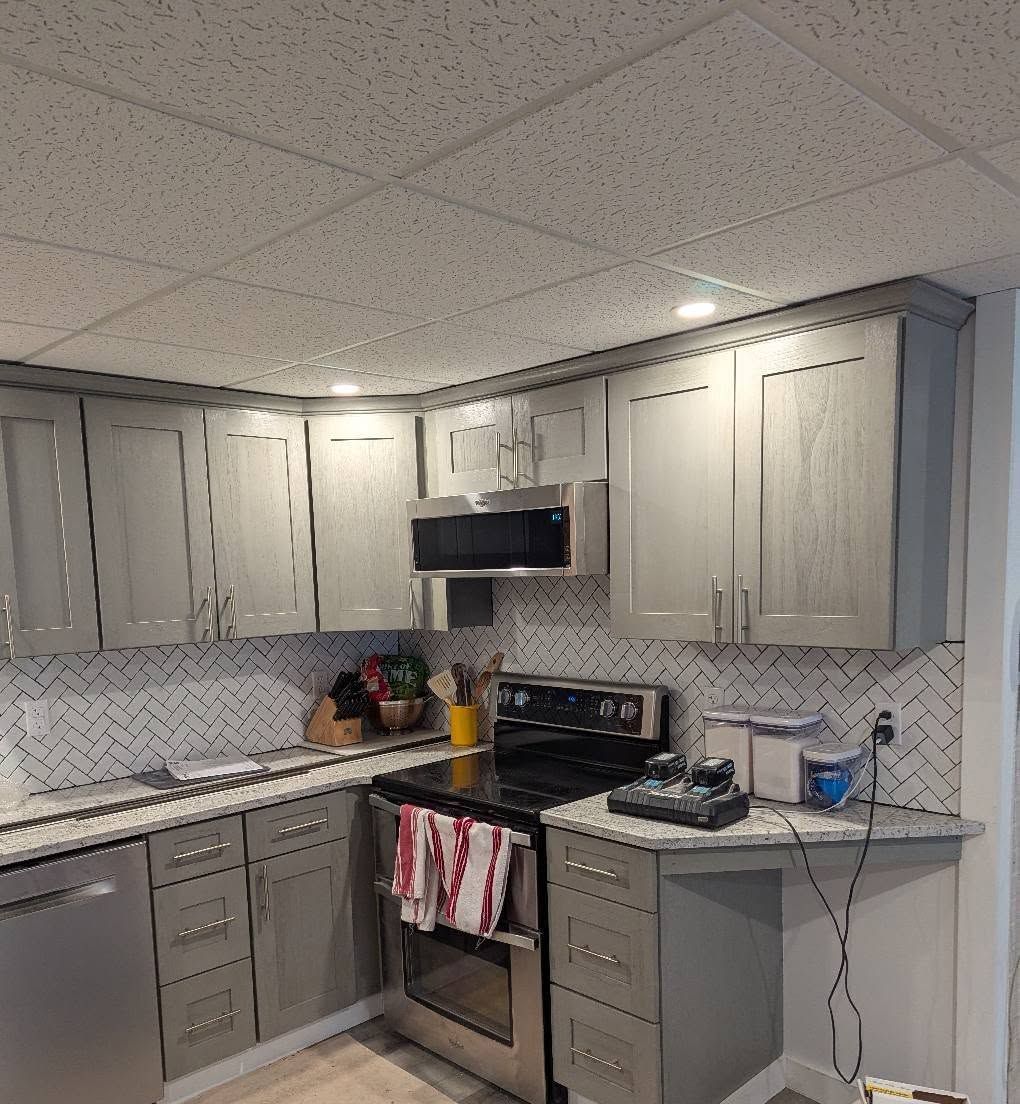 Gray kitchen cabinets with stainless steel appliances and white backsplash.