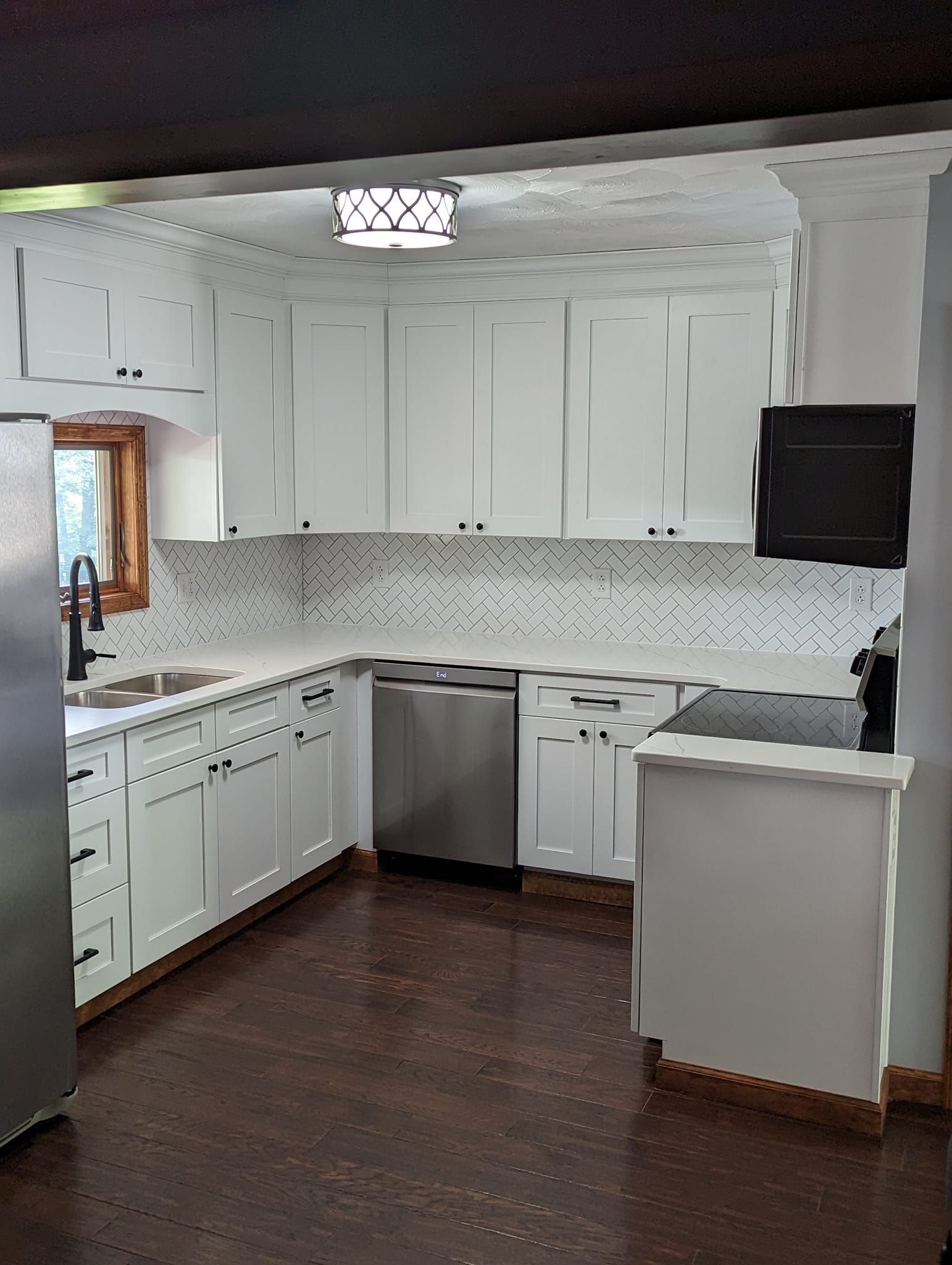 White kitchen cabinets with stainless steel appliances, dark wood floors.