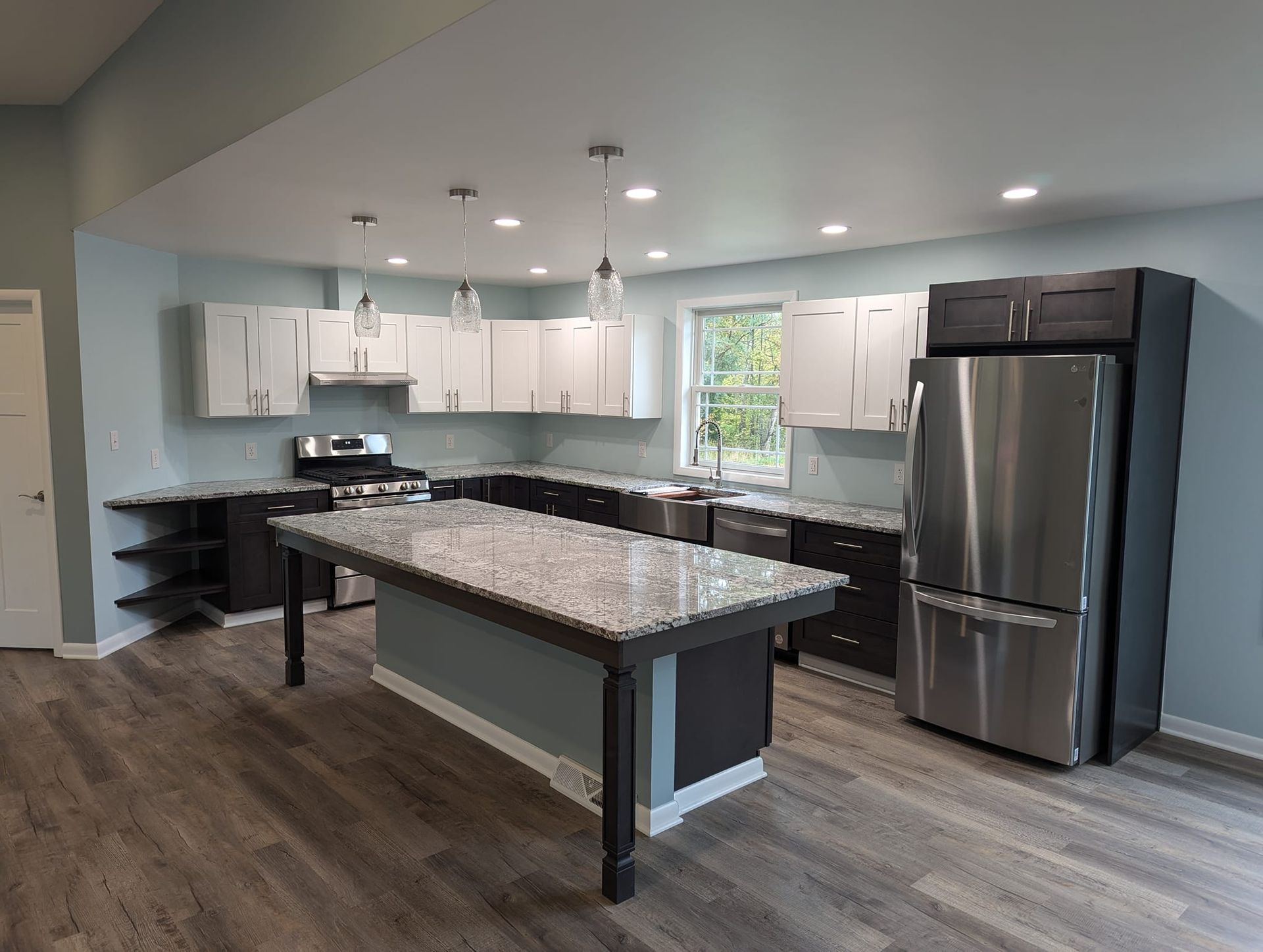 Modern kitchen with white and dark cabinets, granite countertops, and stainless steel appliances.