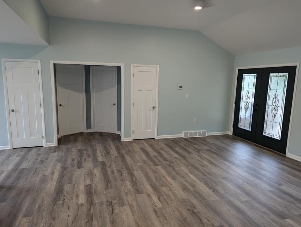 Room interior with light blue walls, gray flooring, white doors, and black double doors.