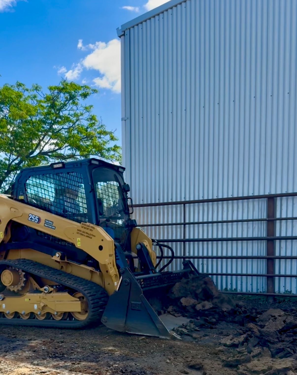 Posi Track cleaning cattle yards, loading manure into truck for agricultural earthworks.