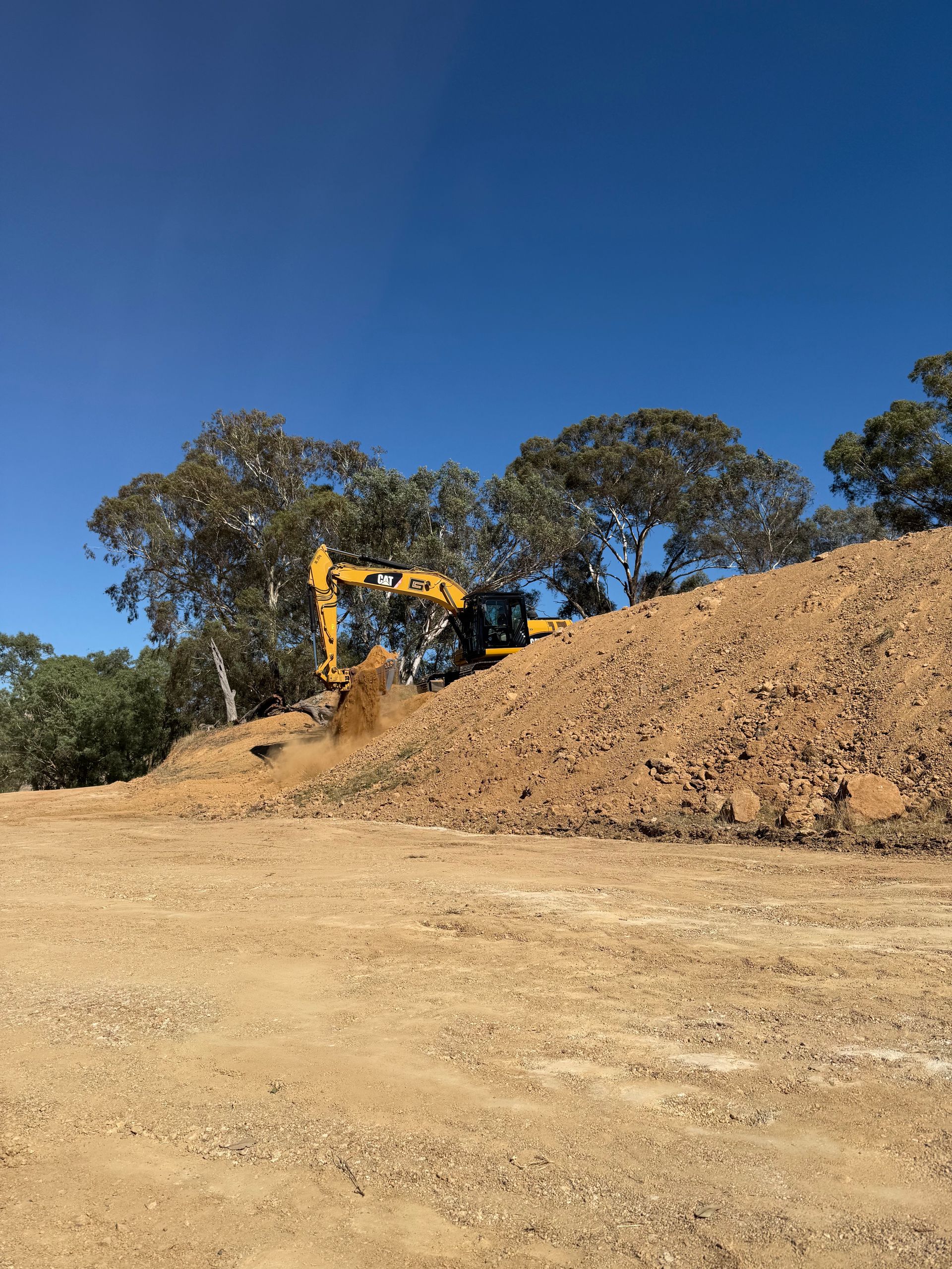 20-tonne excavator on gravel pile, ready to load trucks – efficient earthmoving & material handling. 