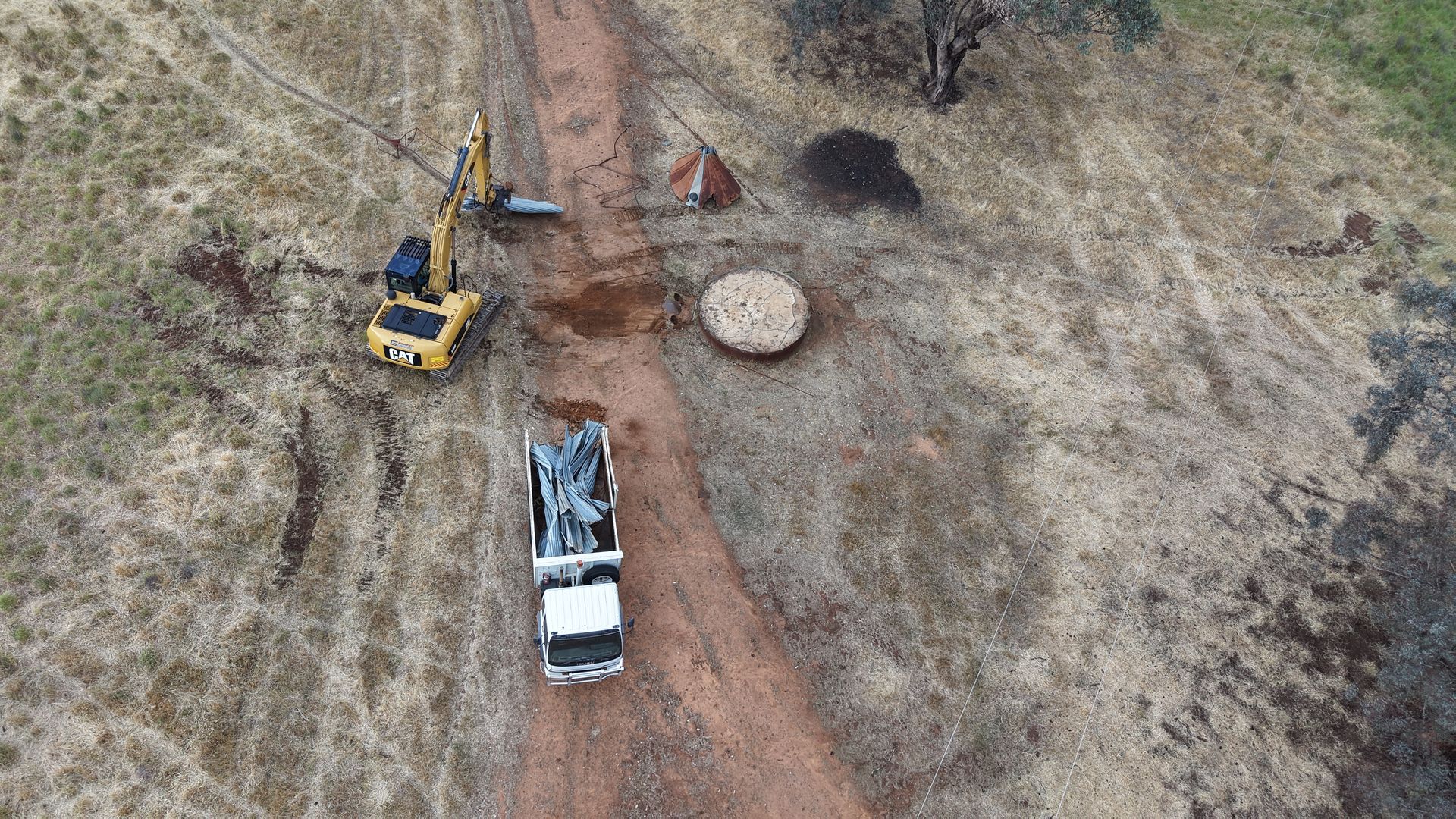Overhead view of rural earthworks in Cowra NSW – excavator, hydraulic grab & truck removing old structures. 
