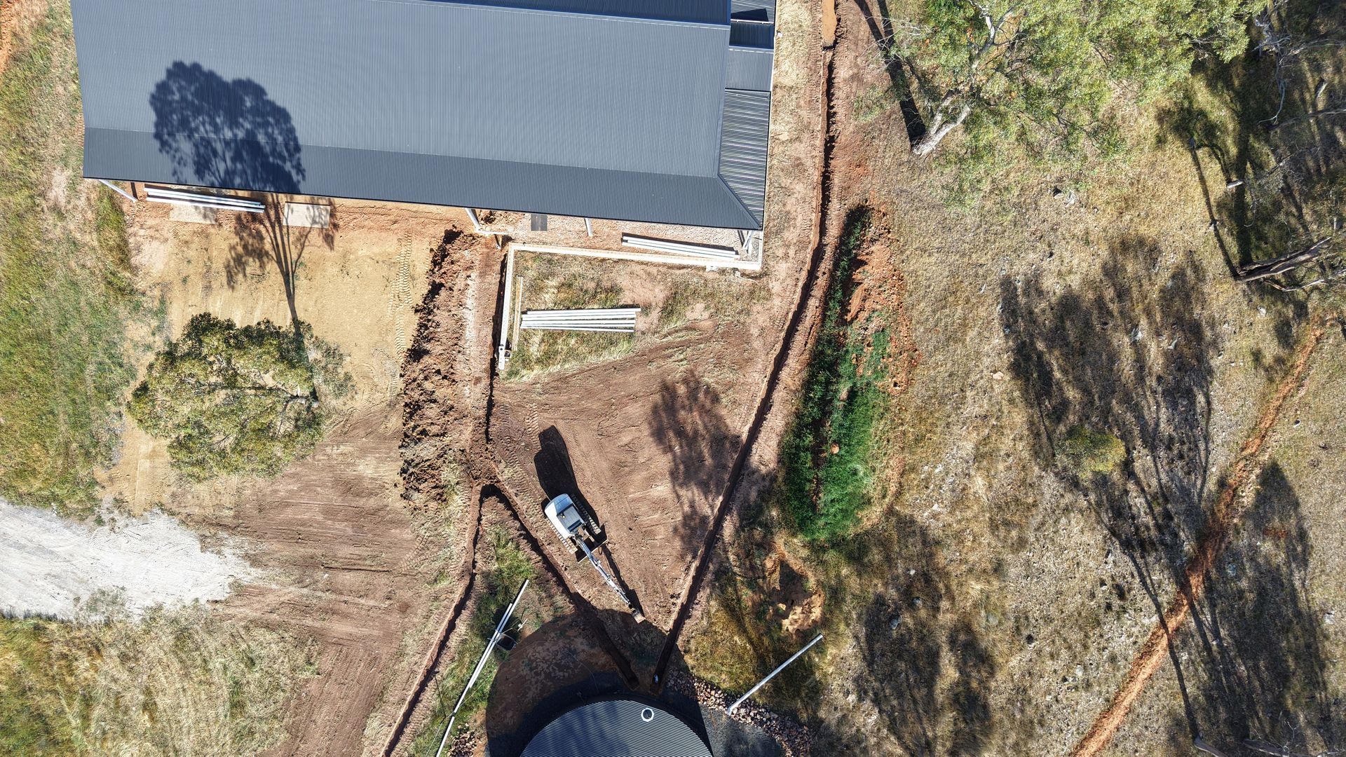 Overhead view of a trench around a shed, prepared for drainage installation, expert civil and rural  earthworks.