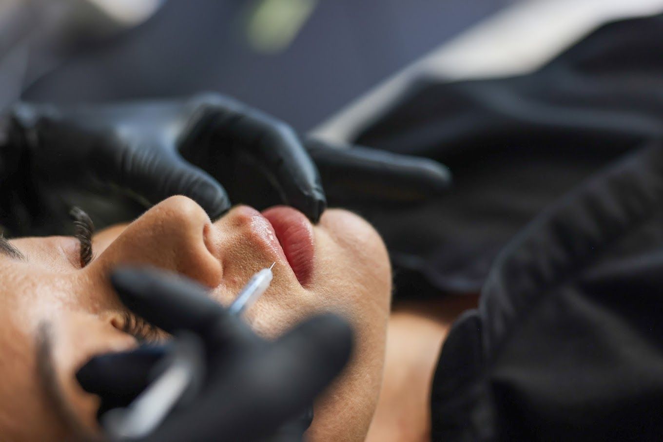 A woman is getting a lip tattoo with a syringe.