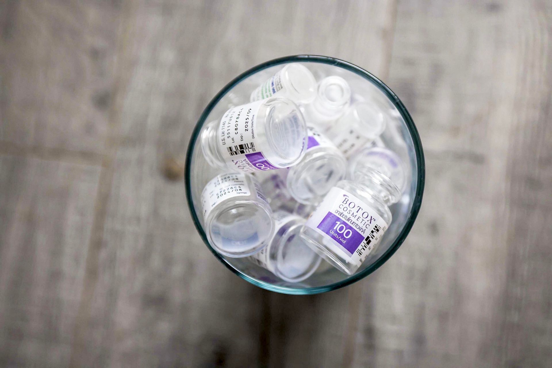 A glass filled with empty bottles on a wooden table.