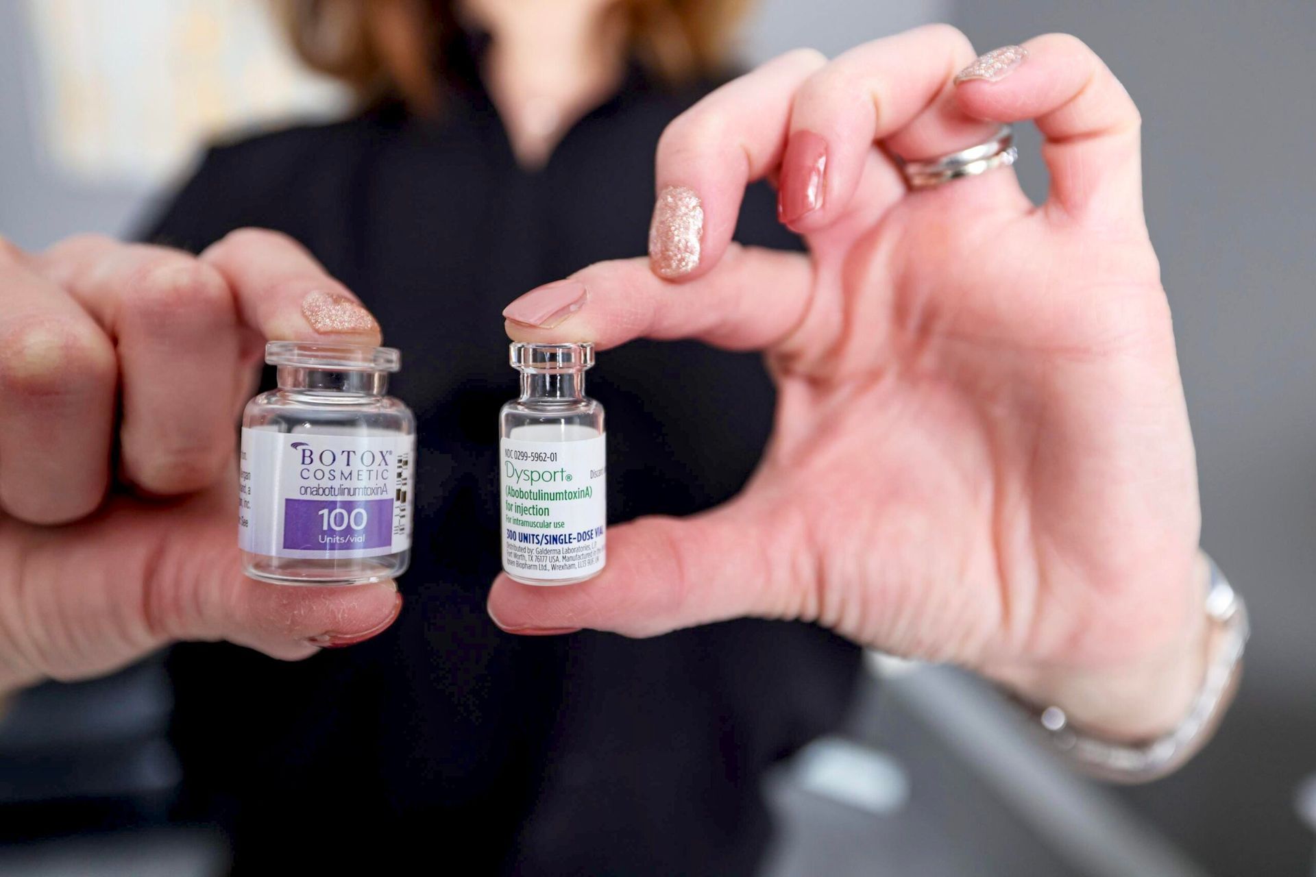 A woman is holding two bottles of botox in her hands.