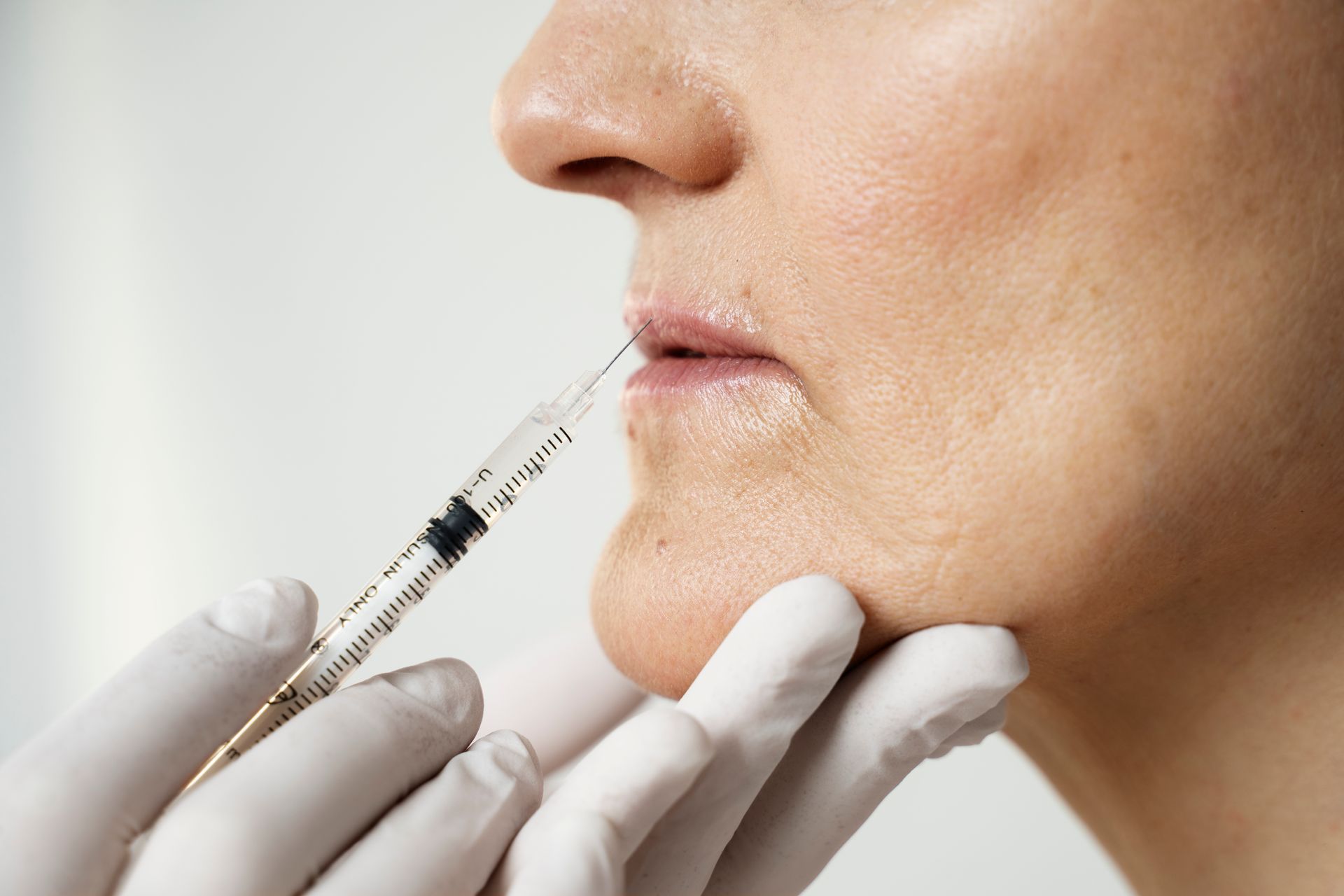 A woman is getting a botox injection in her lips.