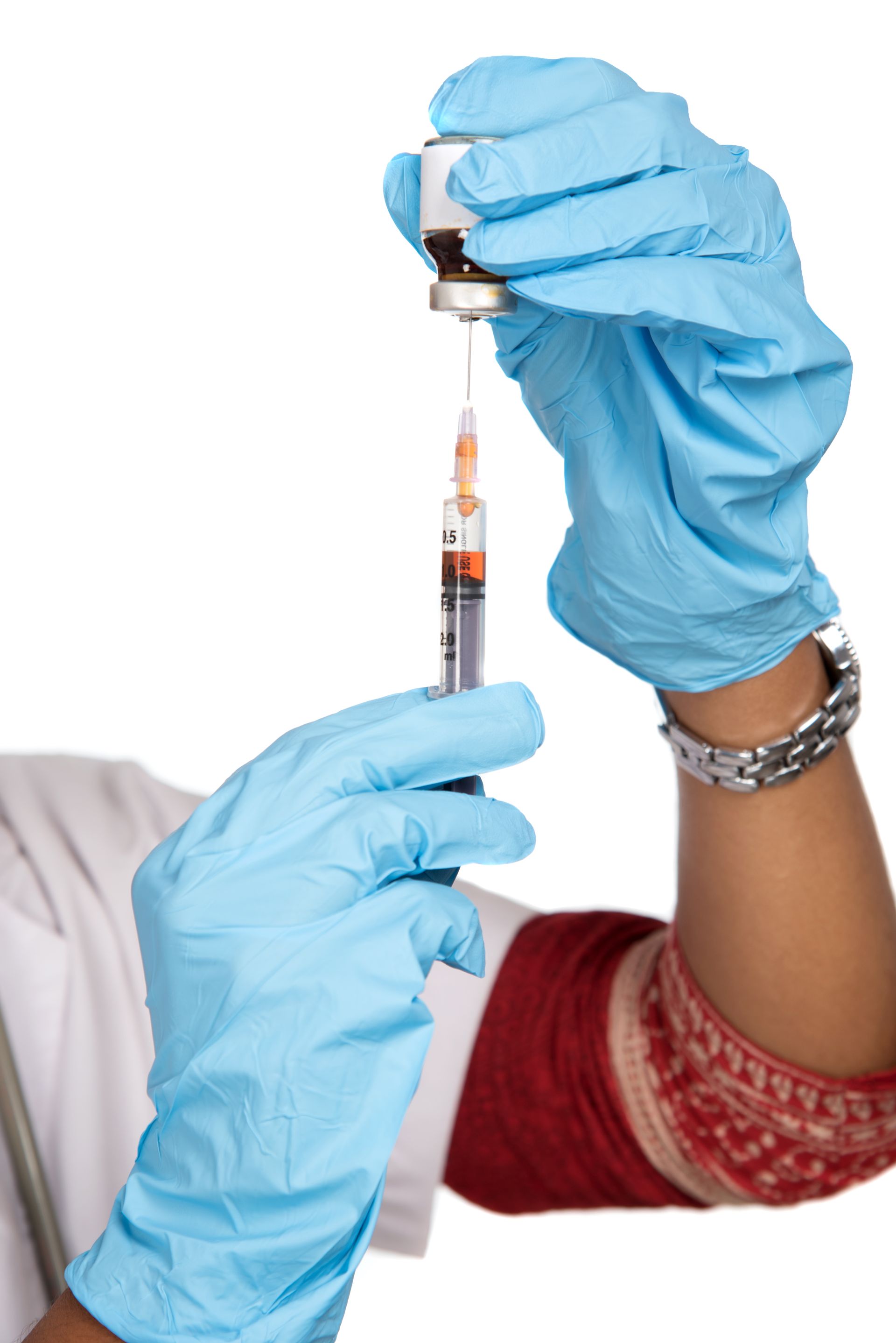 A person wearing blue gloves is holding a syringe