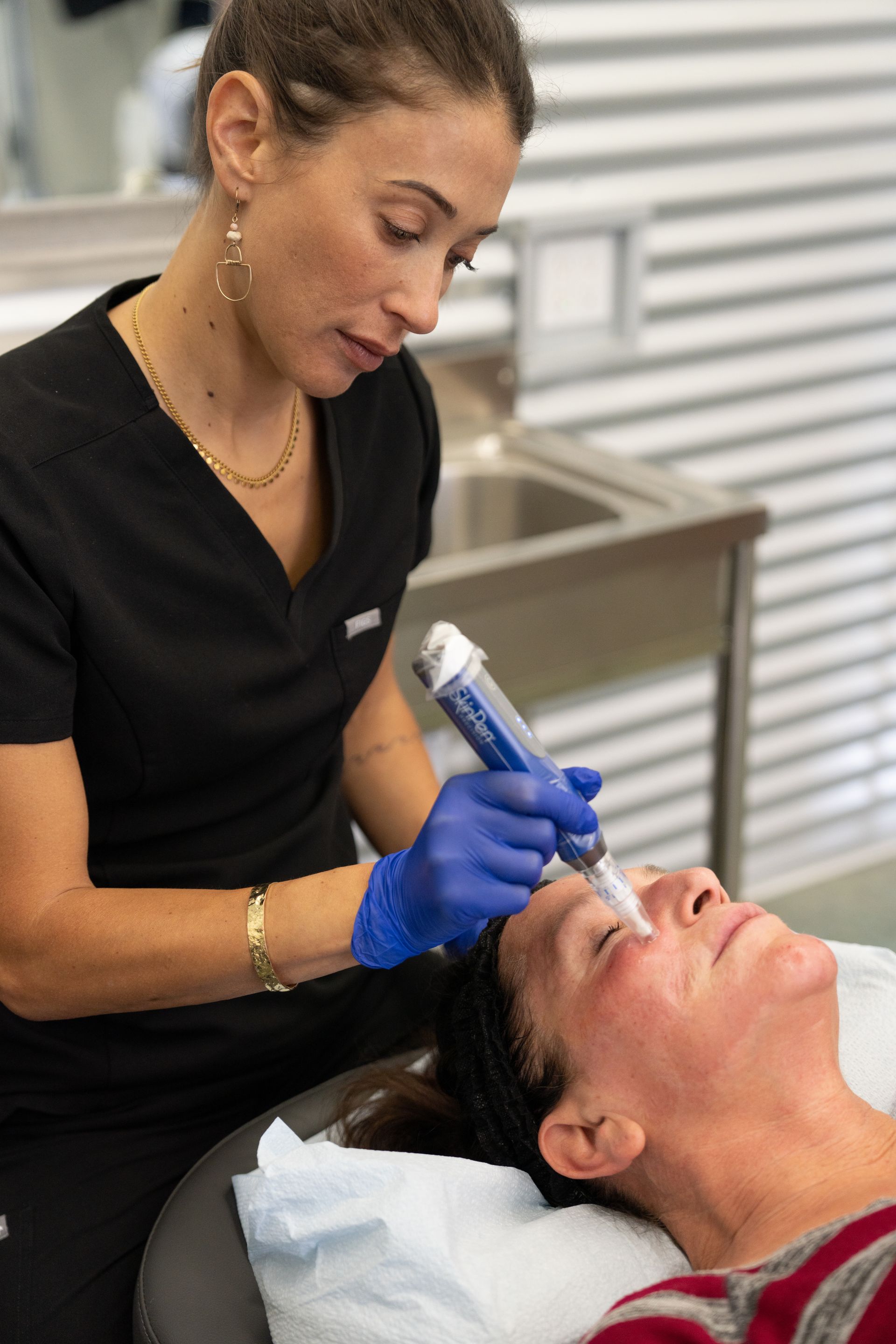 A woman is using a machine on a patient 's face.