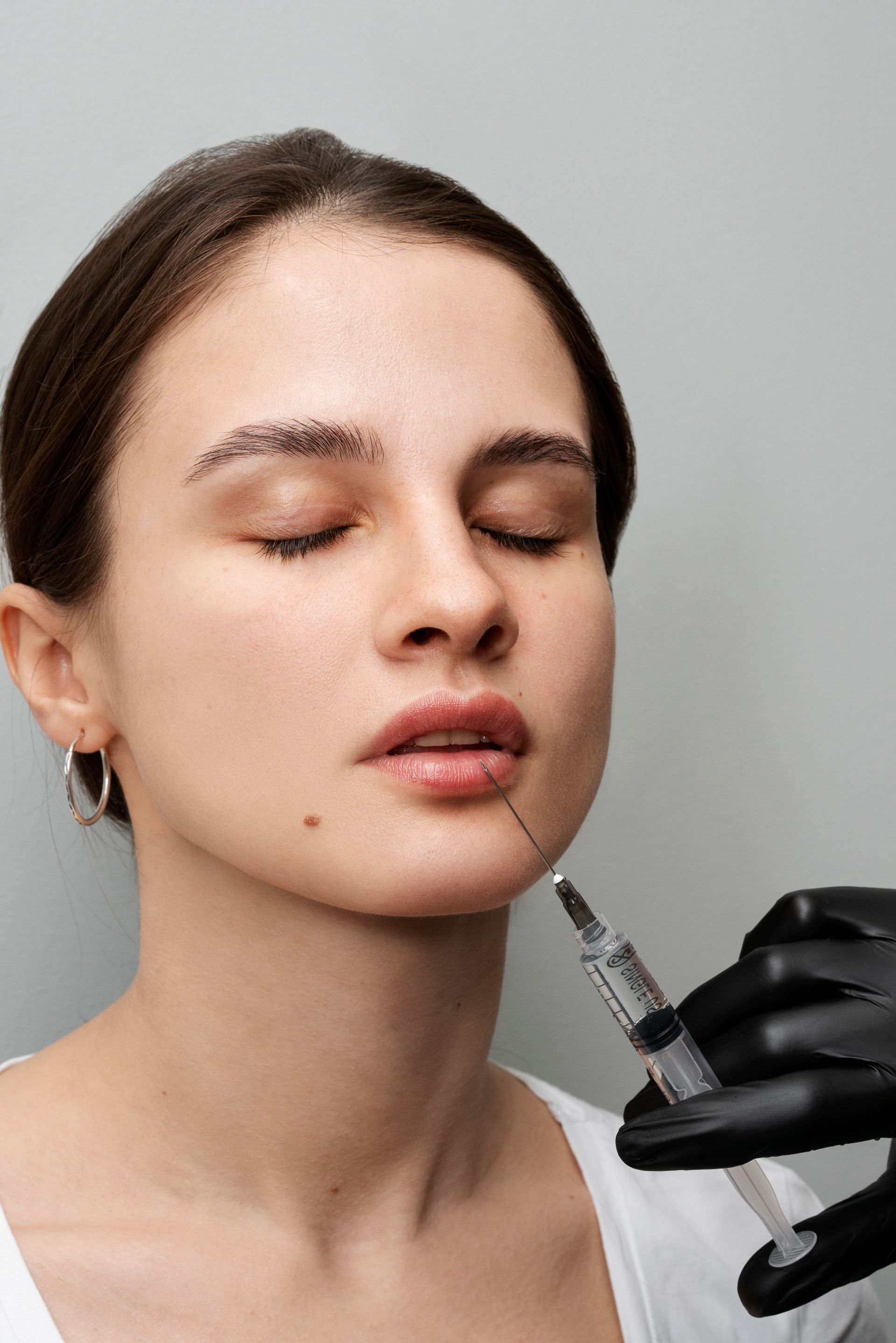 A woman is getting a botox injection in her lip.