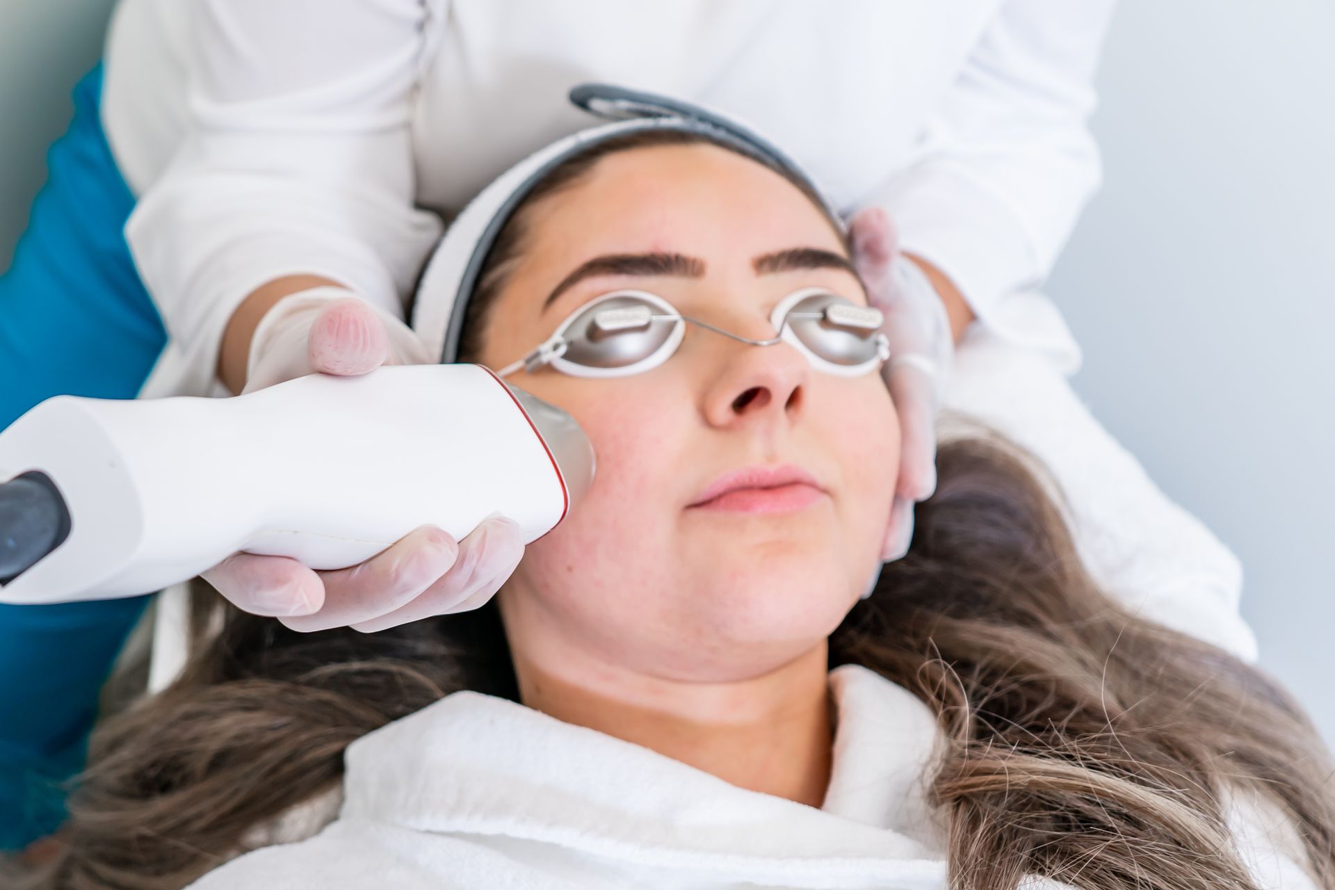 A woman is getting a laser treatment on her face.