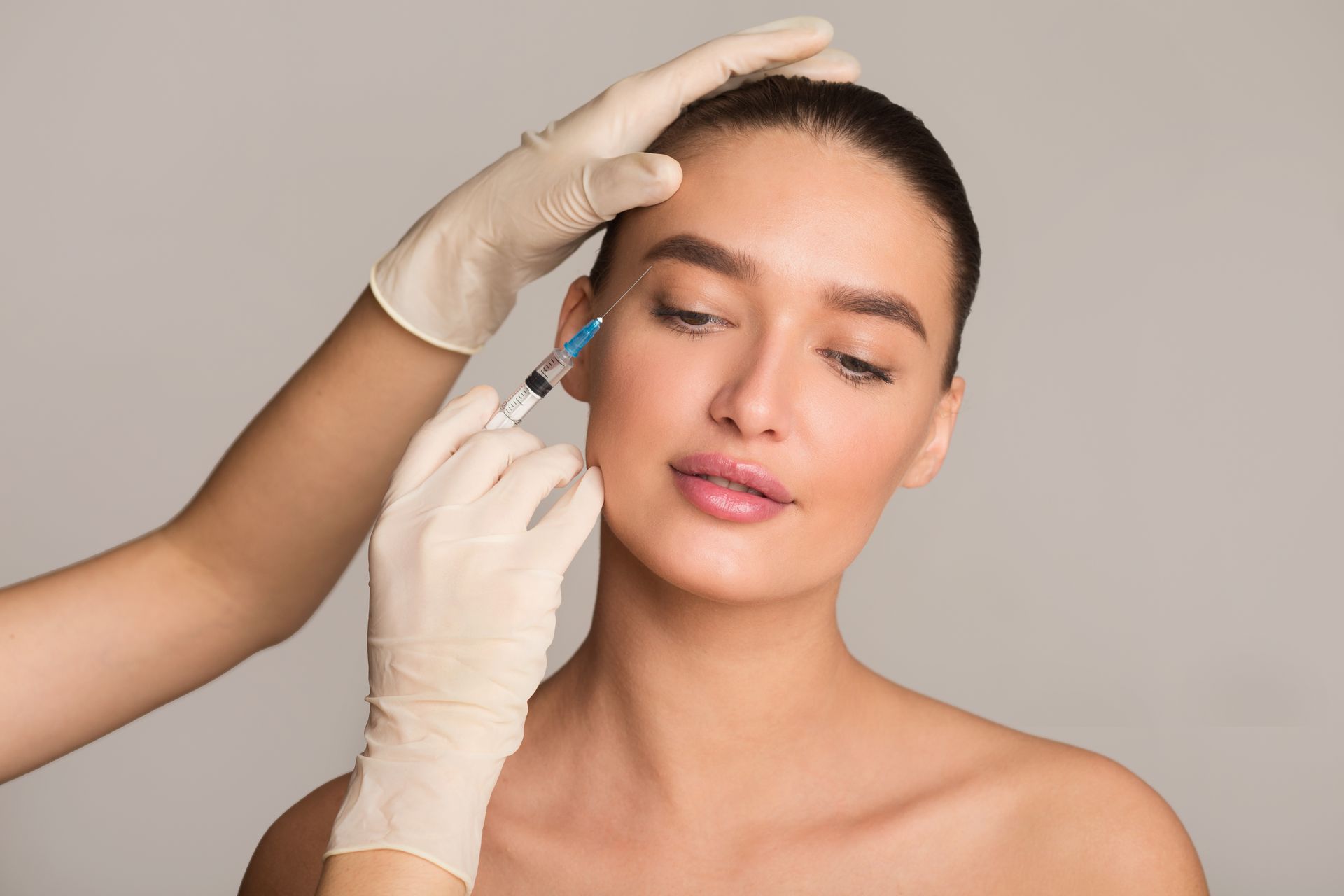 A woman is getting a botox injection in her forehead.