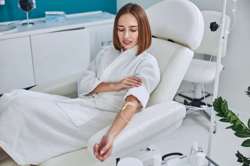 A woman is sitting in a chair with an iv in her arm.