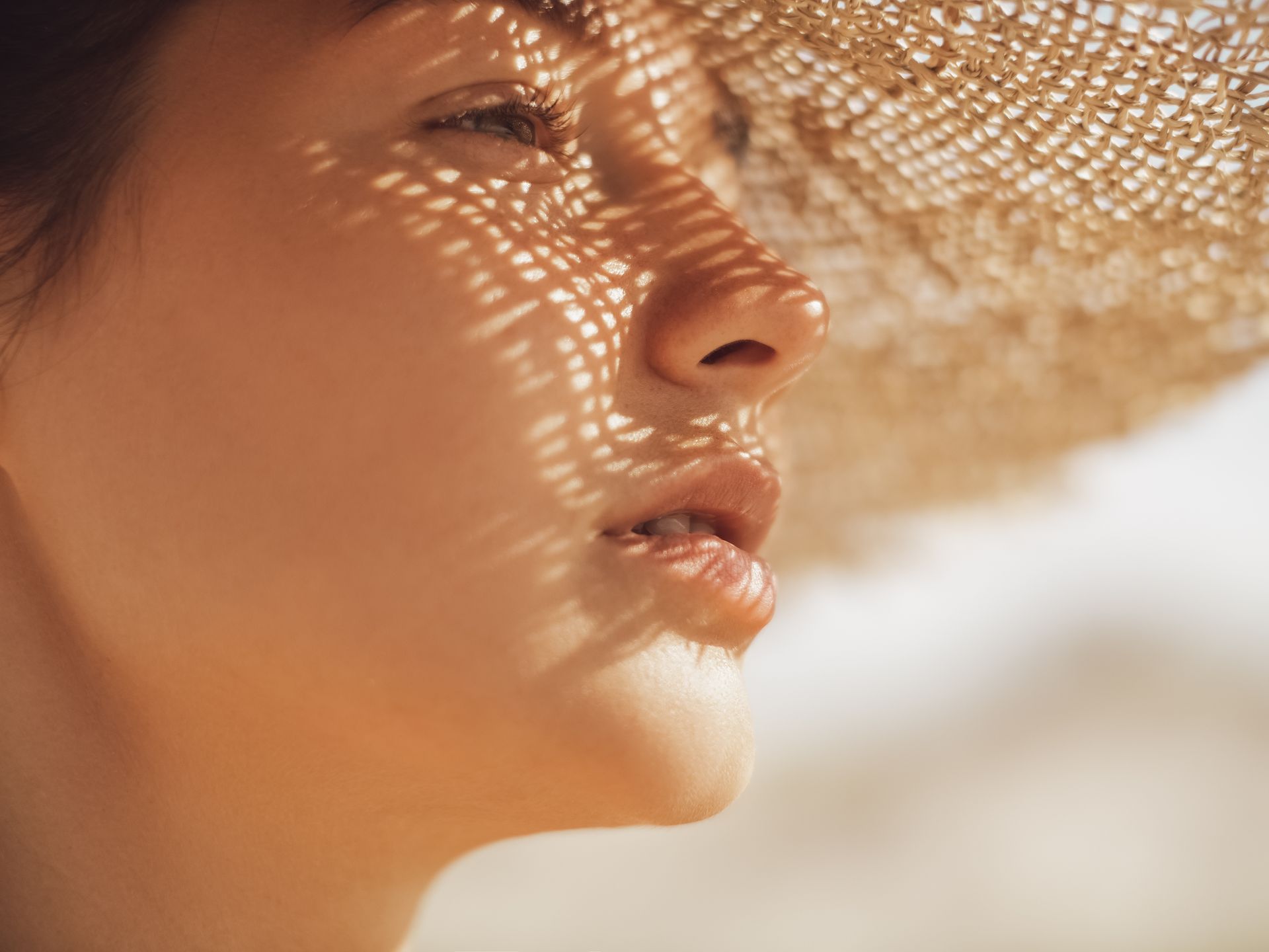 A close up of a woman wearing a straw hat on the beach.