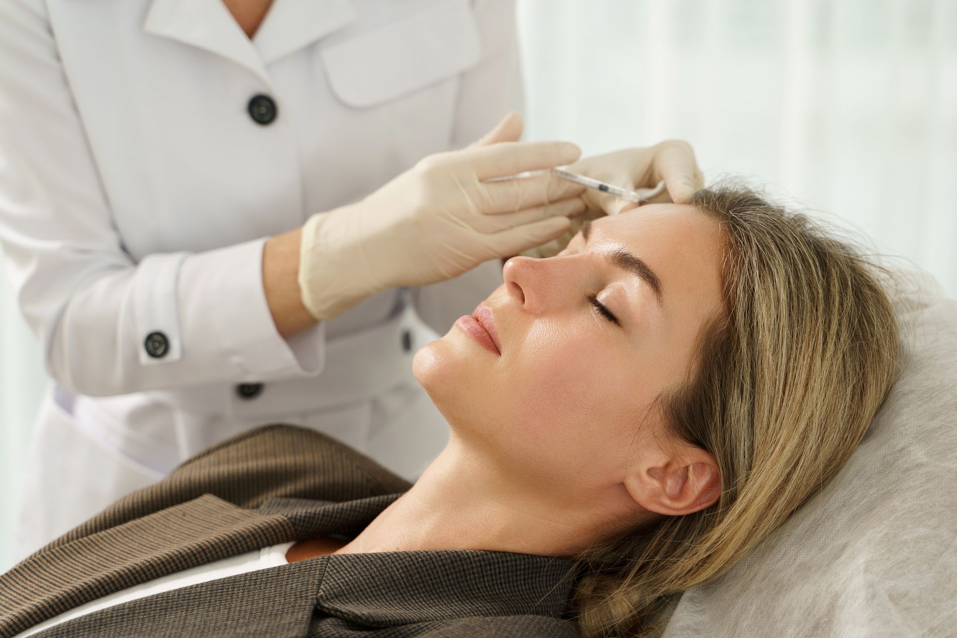 A woman is getting a botox injection in her forehead.