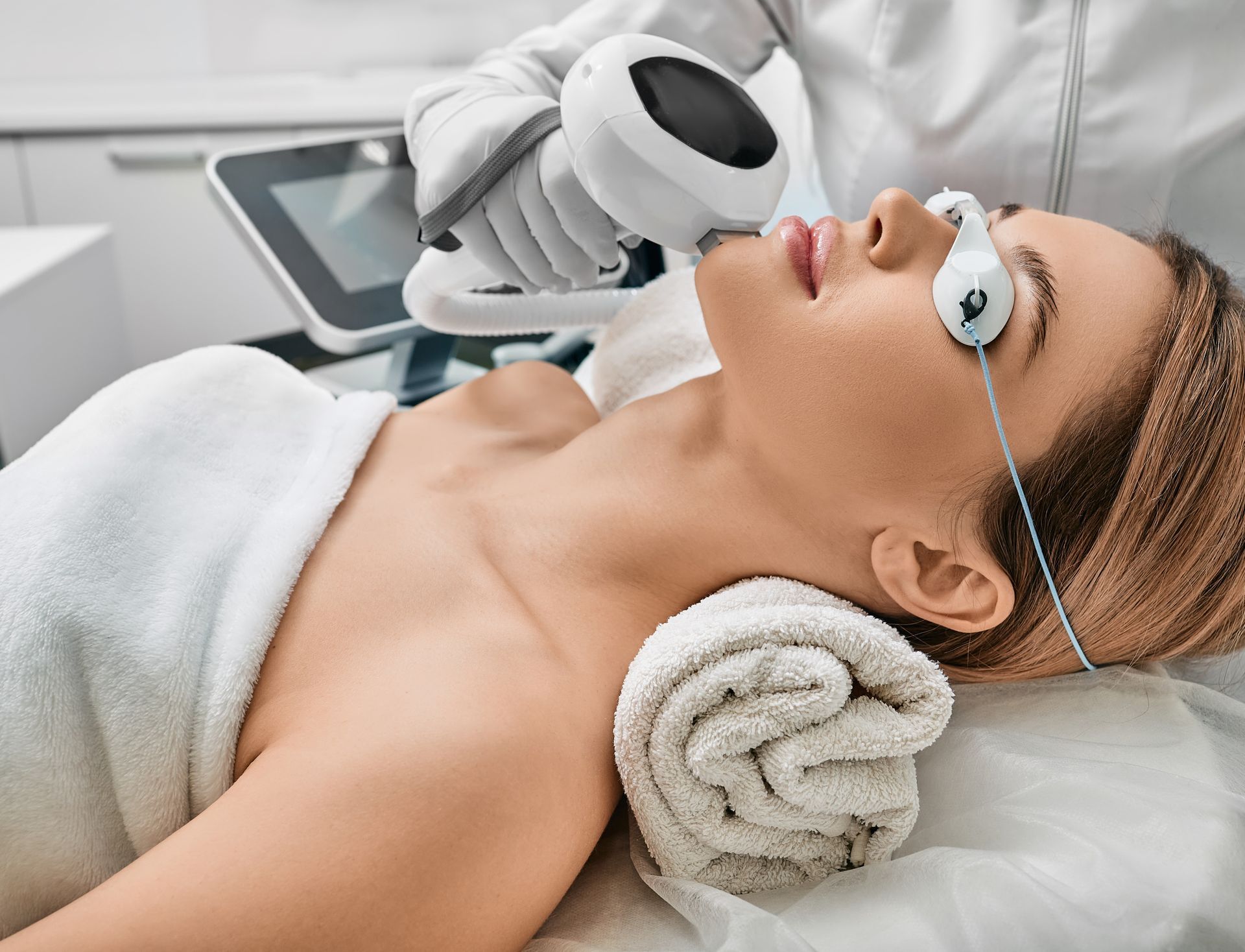 A woman is getting a laser treatment on her face.