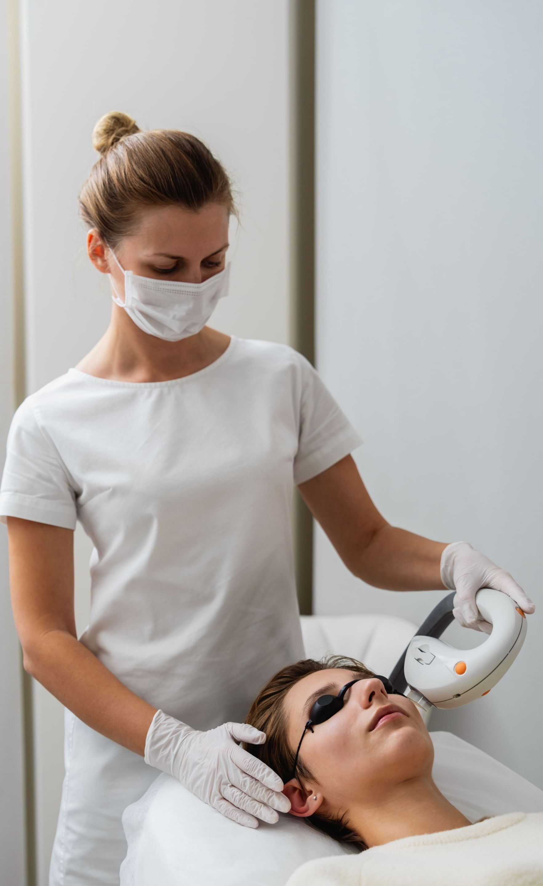 A woman is giving a man a laser treatment on his face.