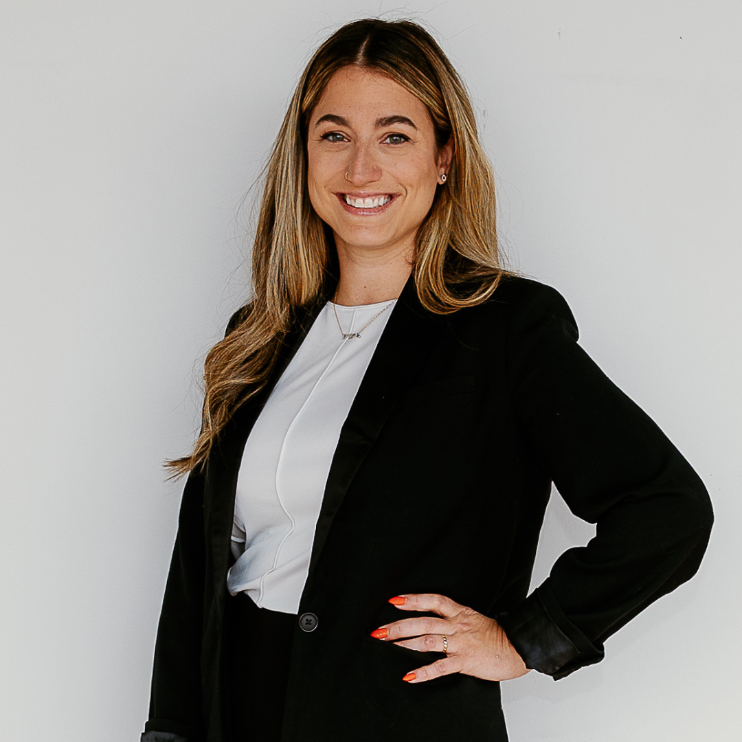 a personal injury attorney in a black top and green skirt is sitting on a stool .