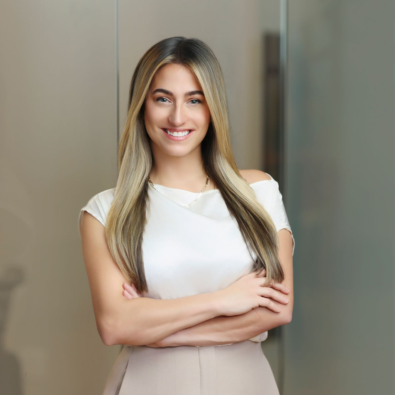 a personal injury attorney in a black top and green skirt is sitting on a stool .