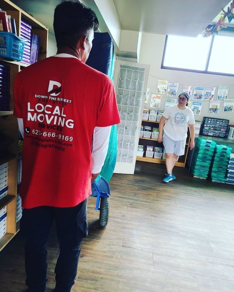 Movers carrying a door inside a store. One man in red shirt, another walking.