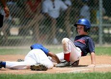 A young boy is sliding into base during a baseball game.