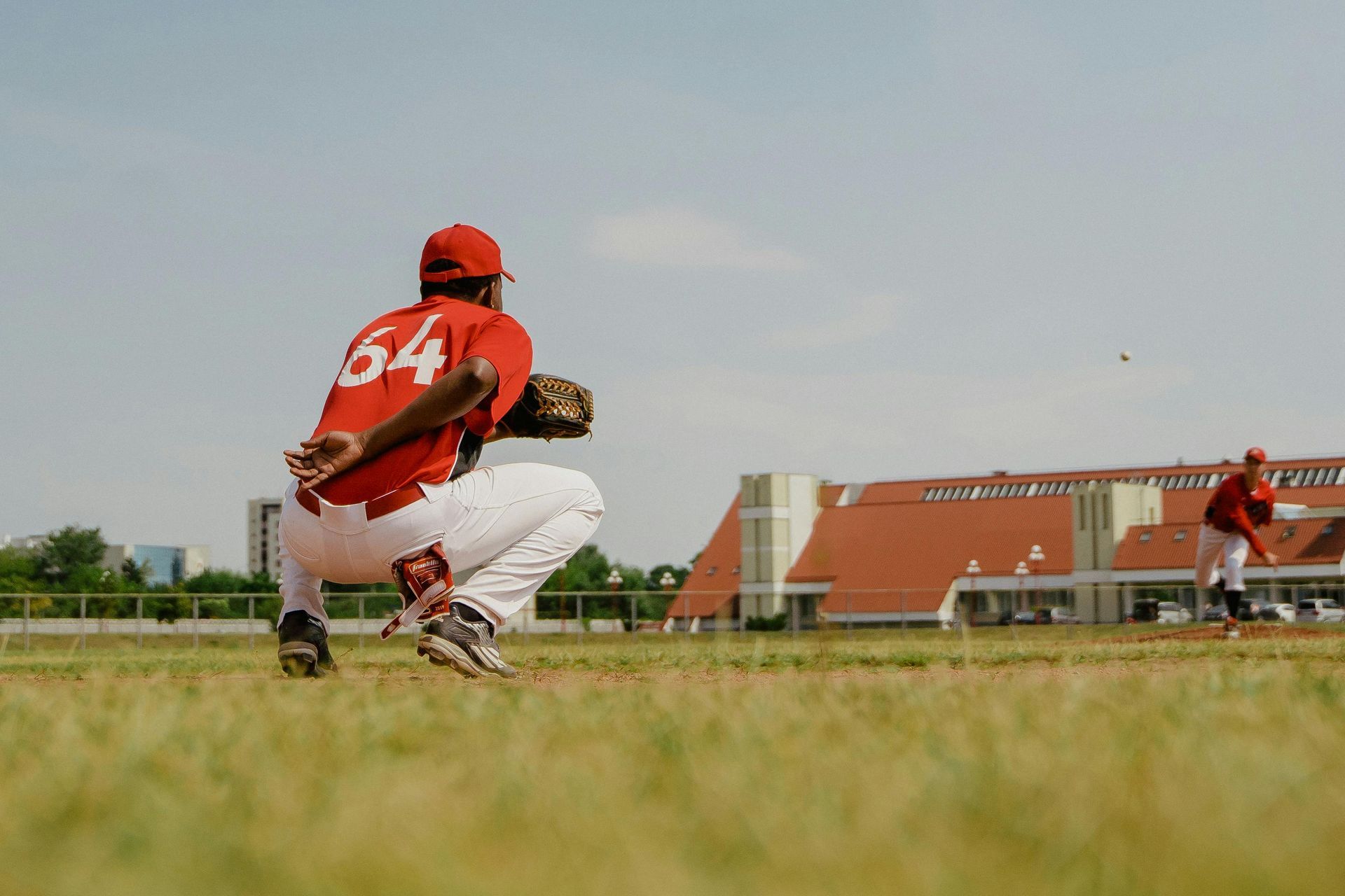 A baseball player in a red uniform is catching a ball on a field.