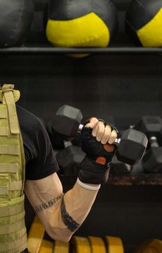 A man is lifting a dumbbell in a gym.
