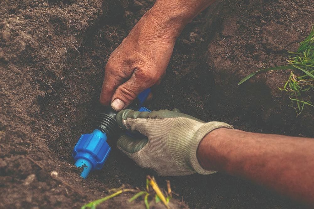 A Blue Pipe Is Coming out Of a Hole in The Ground — Top To Bottom Plumbing in Garbutt, QLD