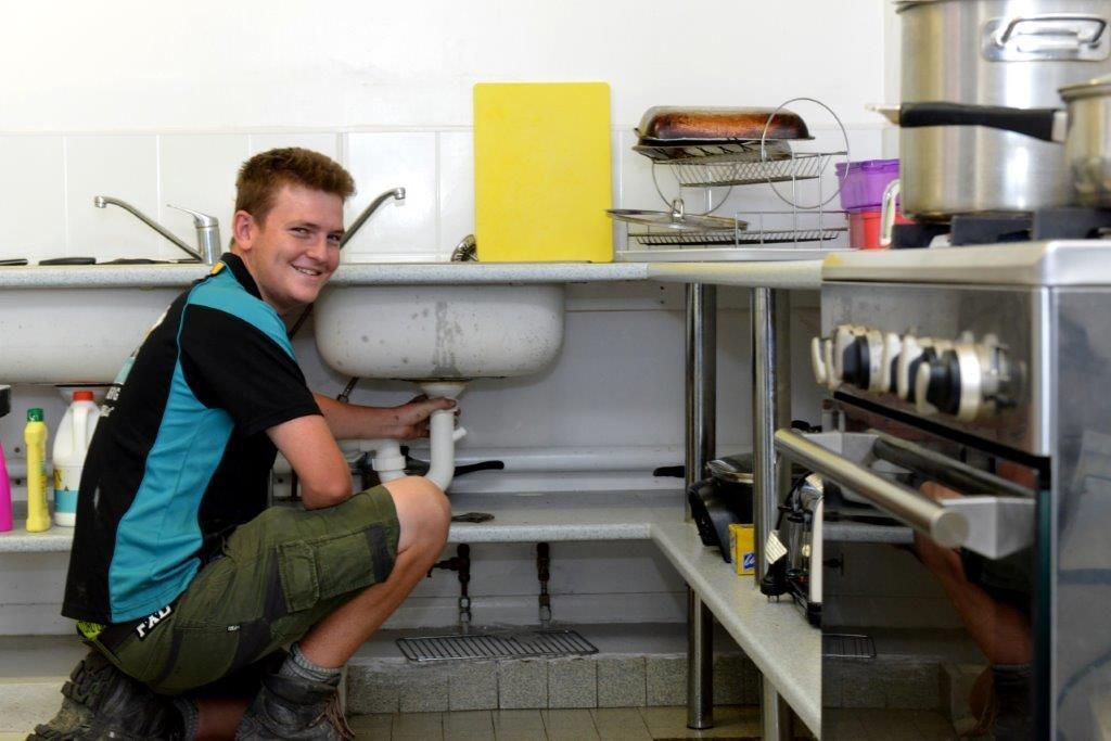 A Person Is Using a Plunger to Unblock a Sink — Top To Bottom Plumbing in Garbutt, QLD
