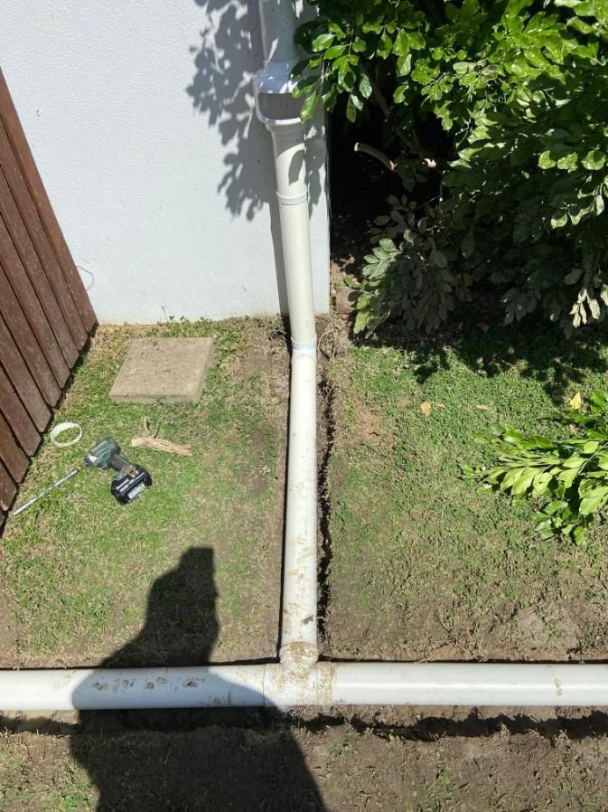 A White Pipe Is Sitting in The Grass Next to A Tree — Top To Bottom Plumbing in Garbutt, QLD
