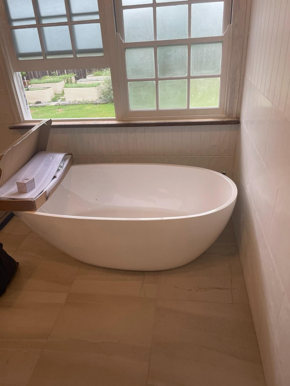 A White Bathtub Is Sitting in A Bathroom Next to A Window — Top To Bottom Plumbing in Garbutt, QLD