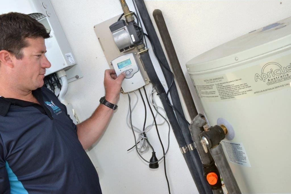 A Man Is Fixing a Pipe with A Wrench — Top To Bottom Plumbing in Garbutt, QLD