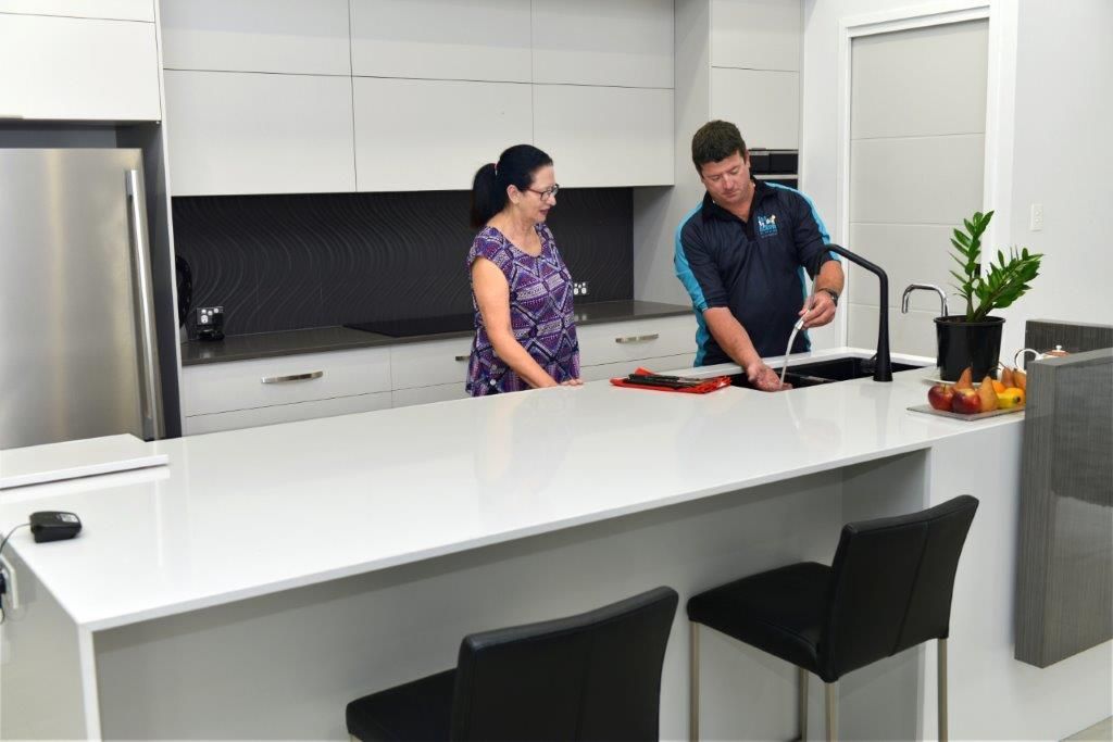 Two Men Are Working on A Dishwasher in A Kitchen — Top To Bottom Plumbing in Garbutt, QLD