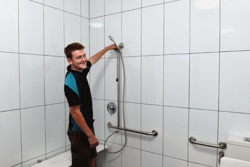 A Shower Head Is Hanging from The Wall in A Bathroom — Top To Bottom Plumbing in Garbutt, QLD