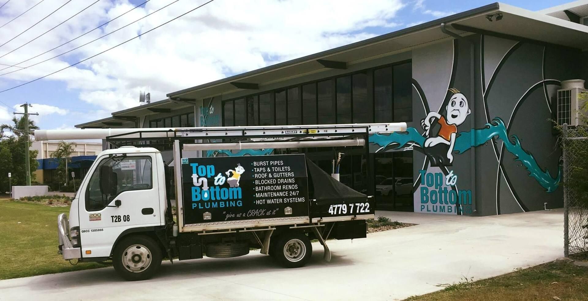A Man Is Working on A Heating System While Holding a Clipboard — Top To Bottom Plumbing in Garbutt, QLD