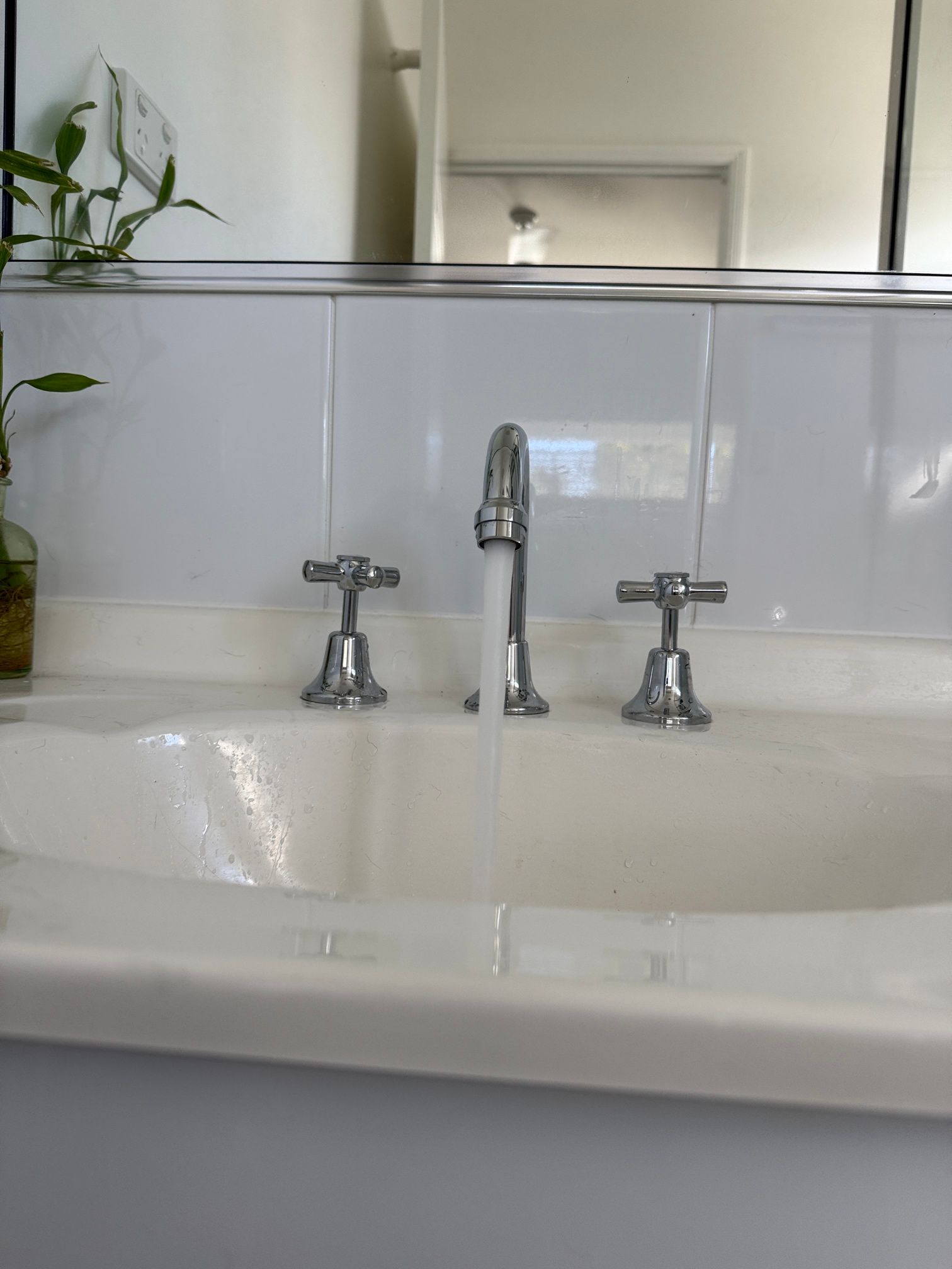 A Man Is Fixing a Faucet in A Bathroom with A Wrench — Top To Bottom Plumbing in Garbutt, QLD