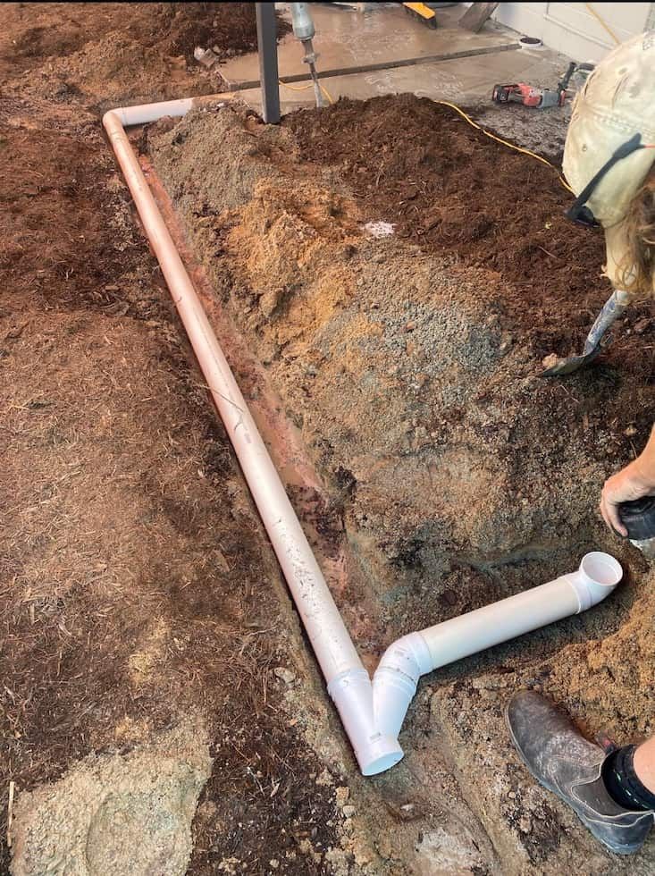 A Person is Installing White Pvc Pipes in a Dug Trench
