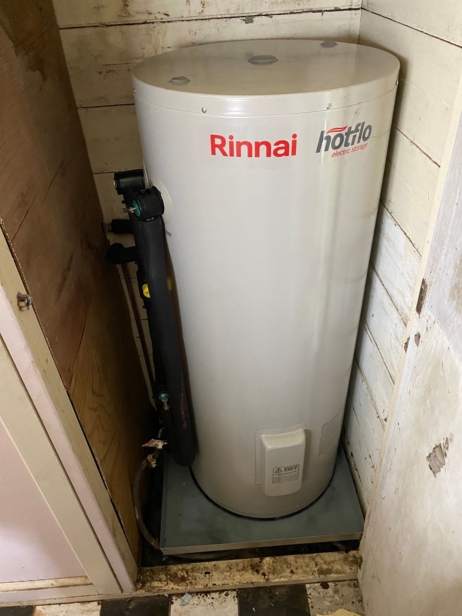 A Person Is Fixing a Water Heater with An Orange Valve — Top To Bottom Plumbing in Garbutt, QLD