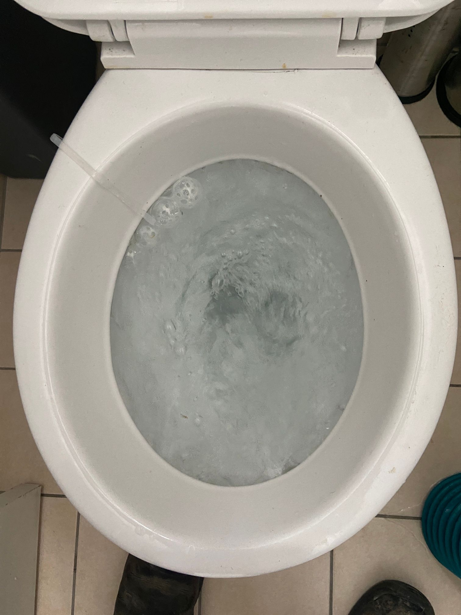 A Man Is Using a Green Plunger to Unblock a Toilet — Top To Bottom Plumbing in Garbutt, QLD