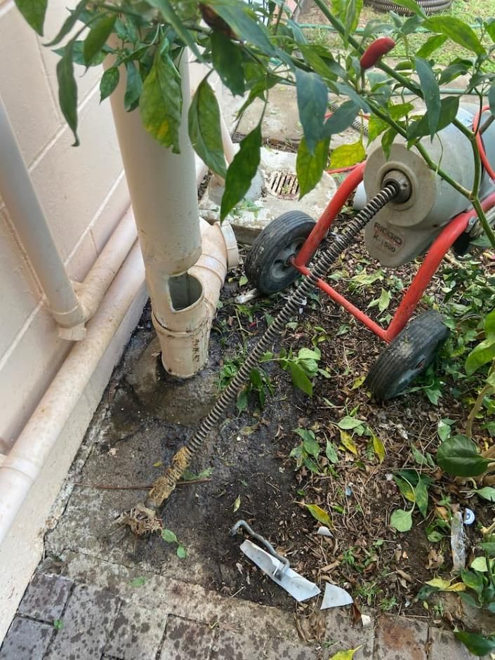 A Drain Cleaner Is Sitting on The Ground Next to A Drain Pipe — Top To Bottom Plumbing in Garbutt, QLD